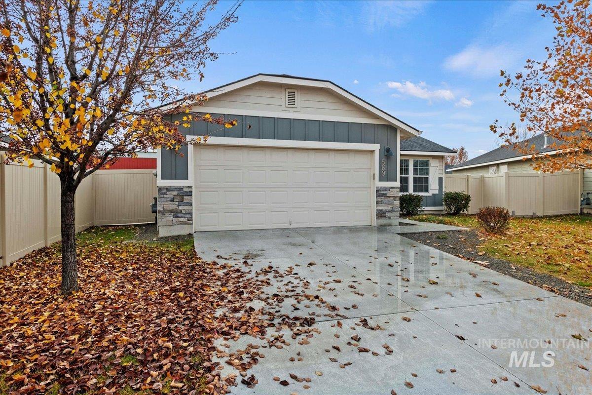 Ranch-style home with stone siding, board and batten siding, concrete driveway, and an attached garage