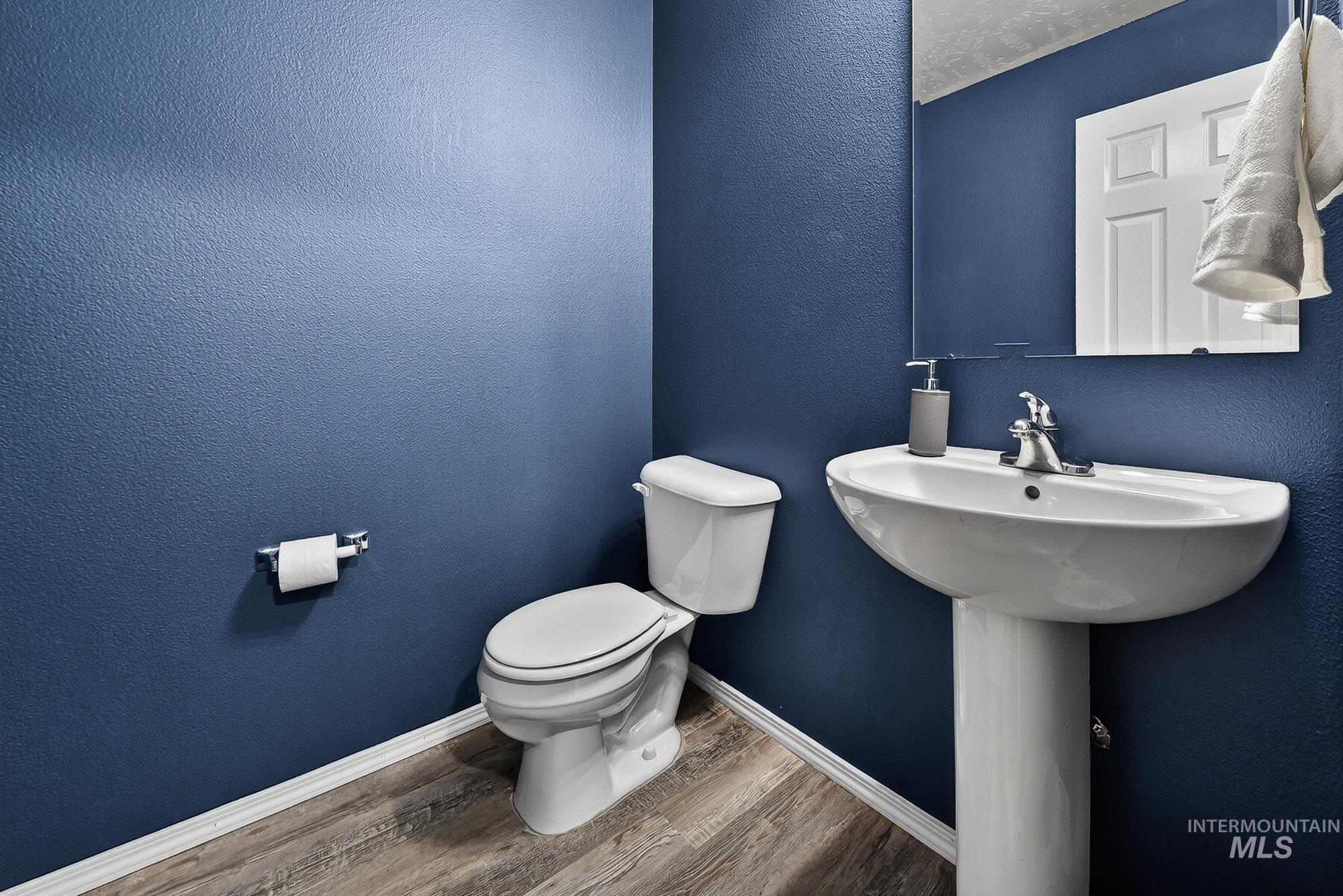 Half bath with a textured wall and laminate wood-like flooring