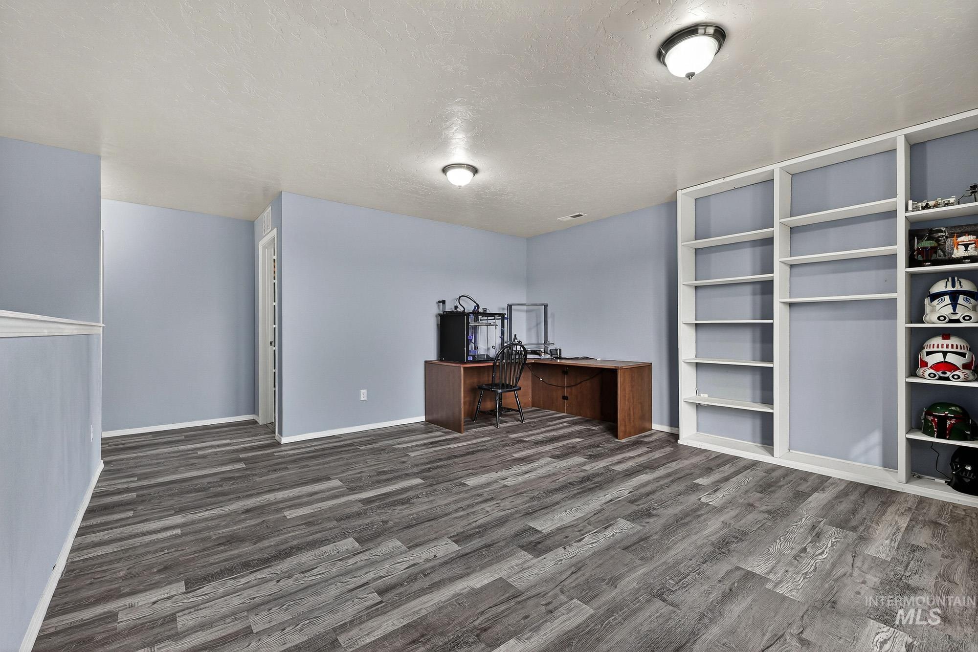 Unfurnished family room with corner used for office  with a textured ceiling and laminate wood-style flooring