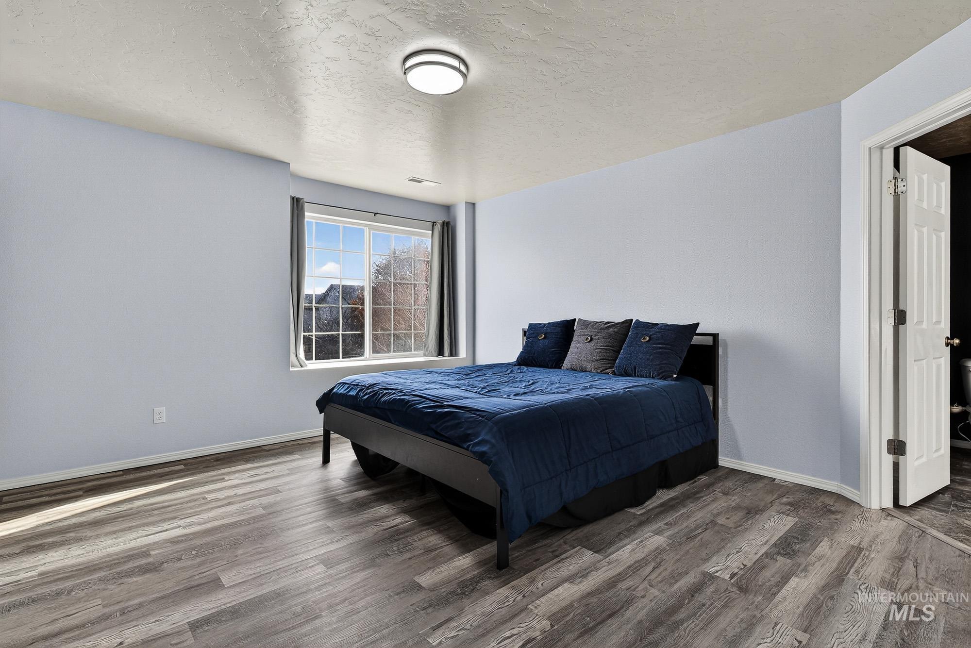 Primary Bedroom Suite with a textured ceiling - pop out window seat and wood like laminate finished floors