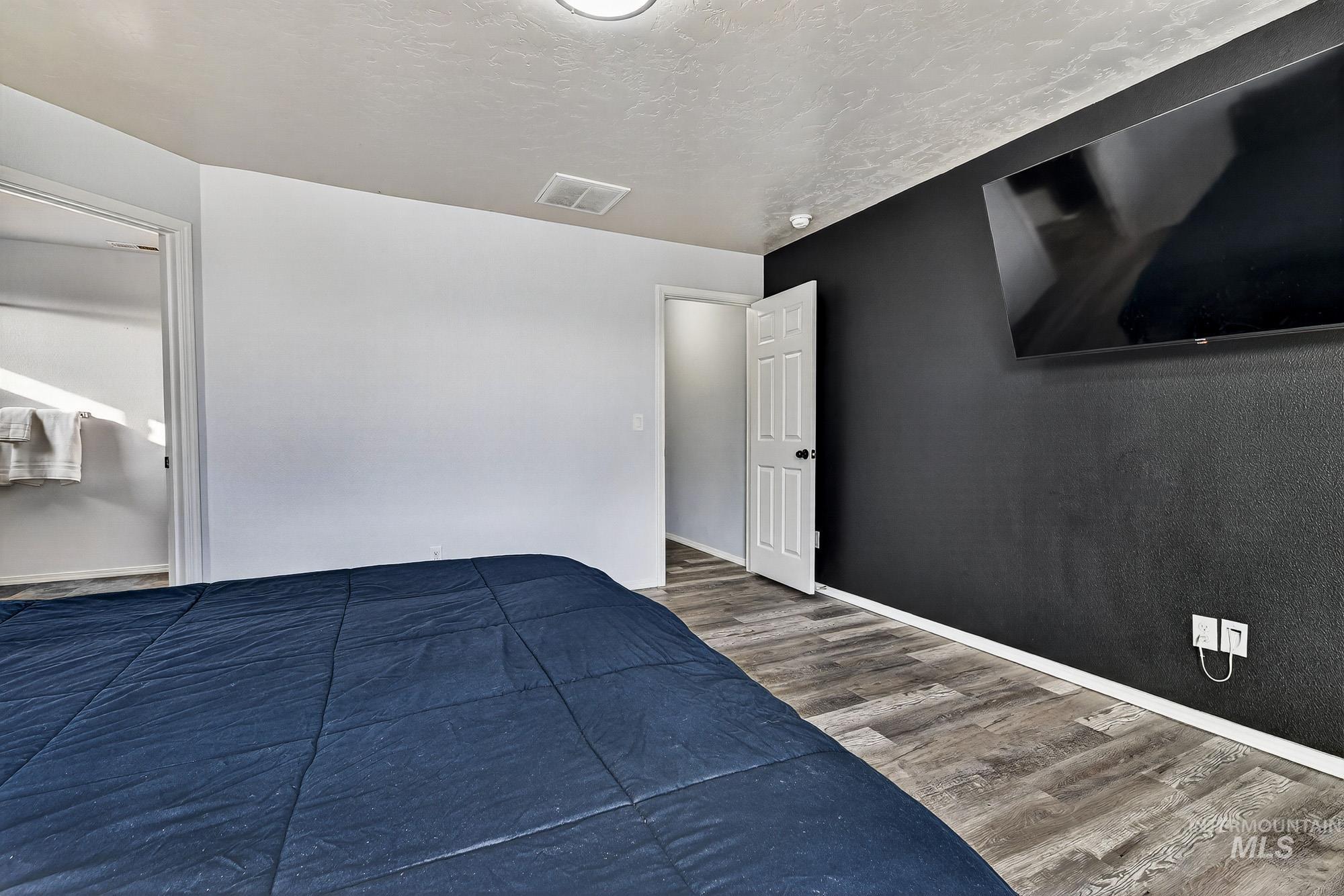 Primary Bedroom Suite with wood like laminate finished floors and a textured ceiling