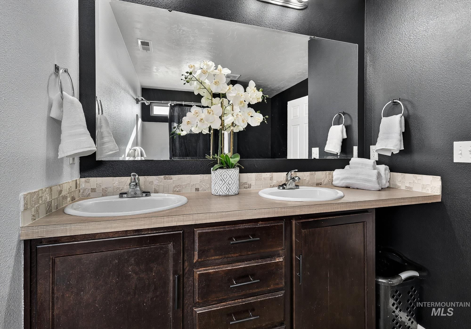 Primary Bathroom featuring a textured wall and double vanity