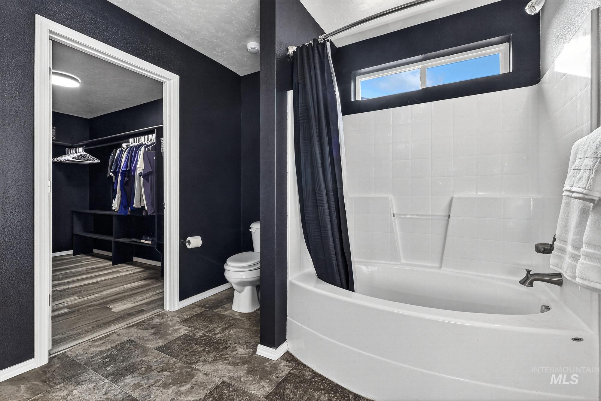 Primary bathroom featuring a walk in closet and shower / oval tub combo