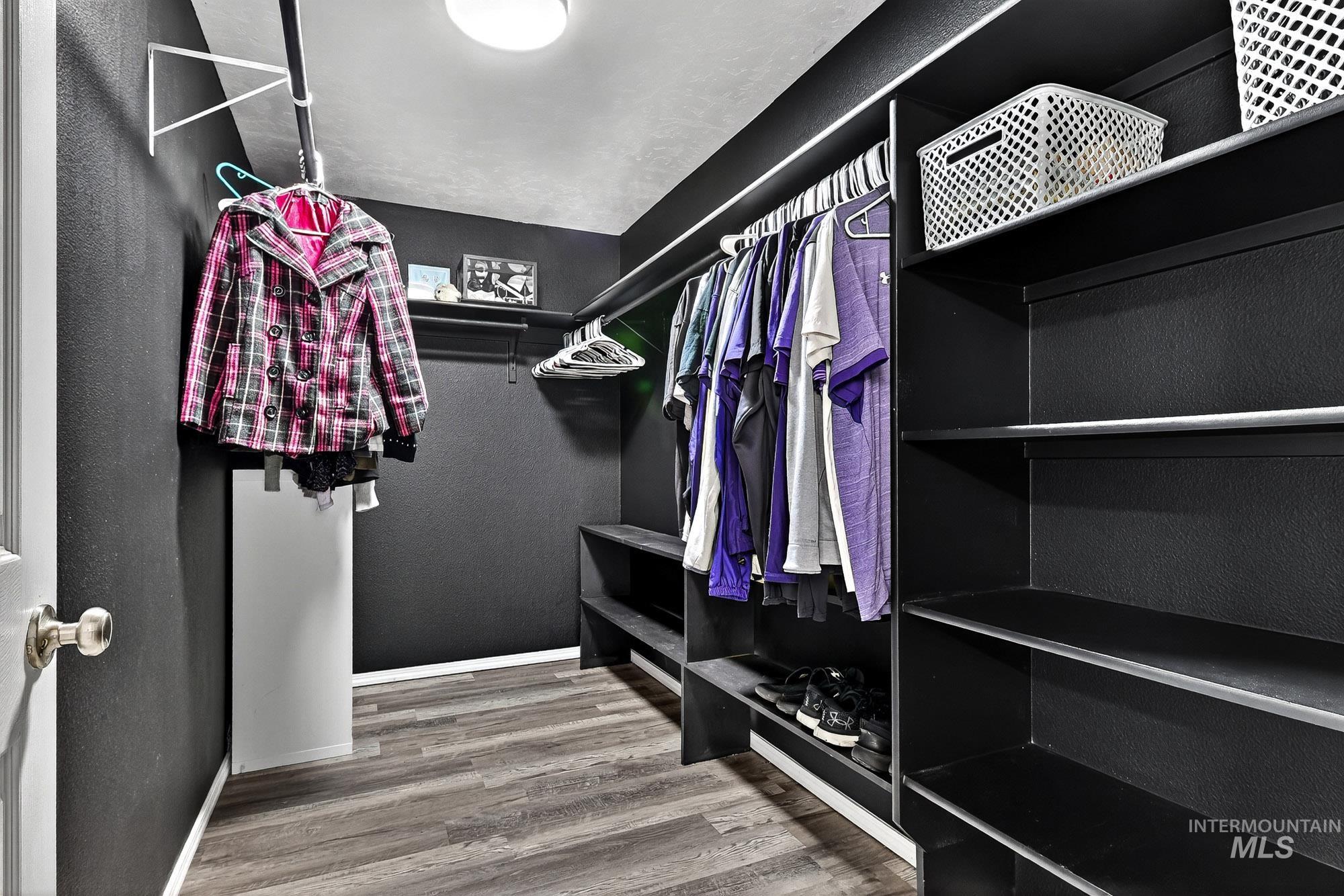 Primary Bedroom Walk in closet with laminate wood like finished floors