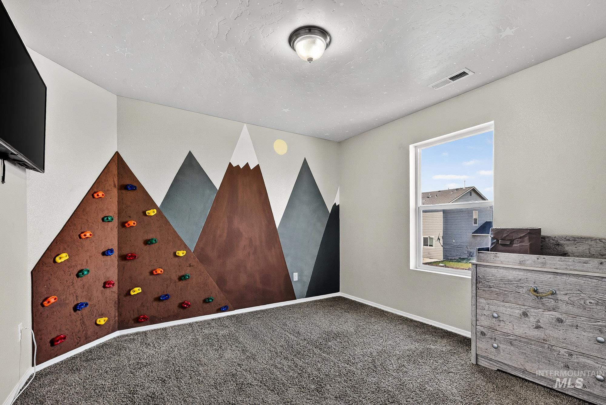 Unfurnished bedroom with a textured ceiling, carpet flooring, and an clever accent wall