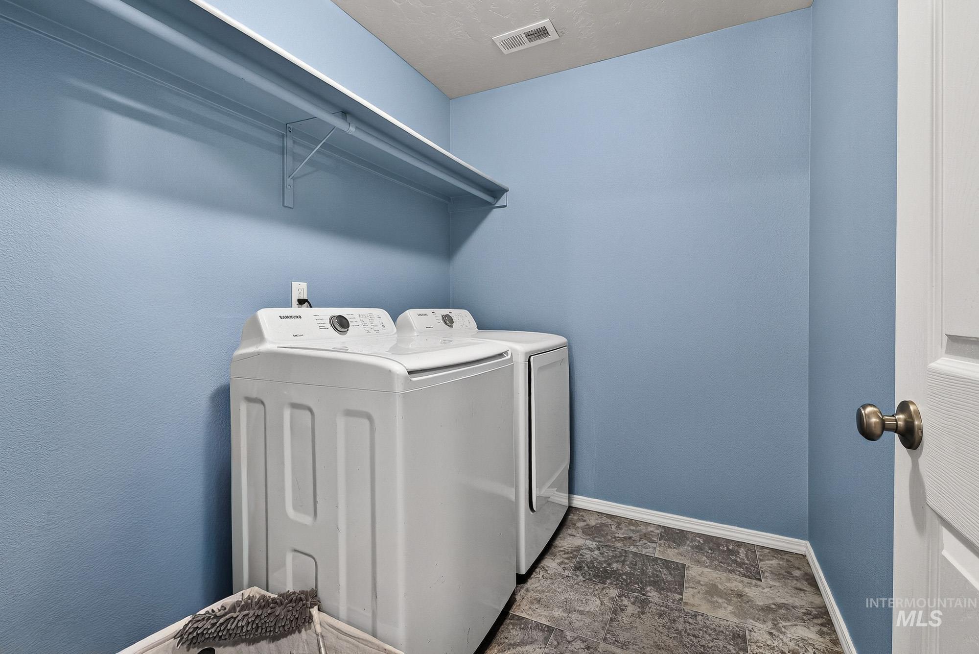 Laundry area with washer and dryer and stone look  finished floors