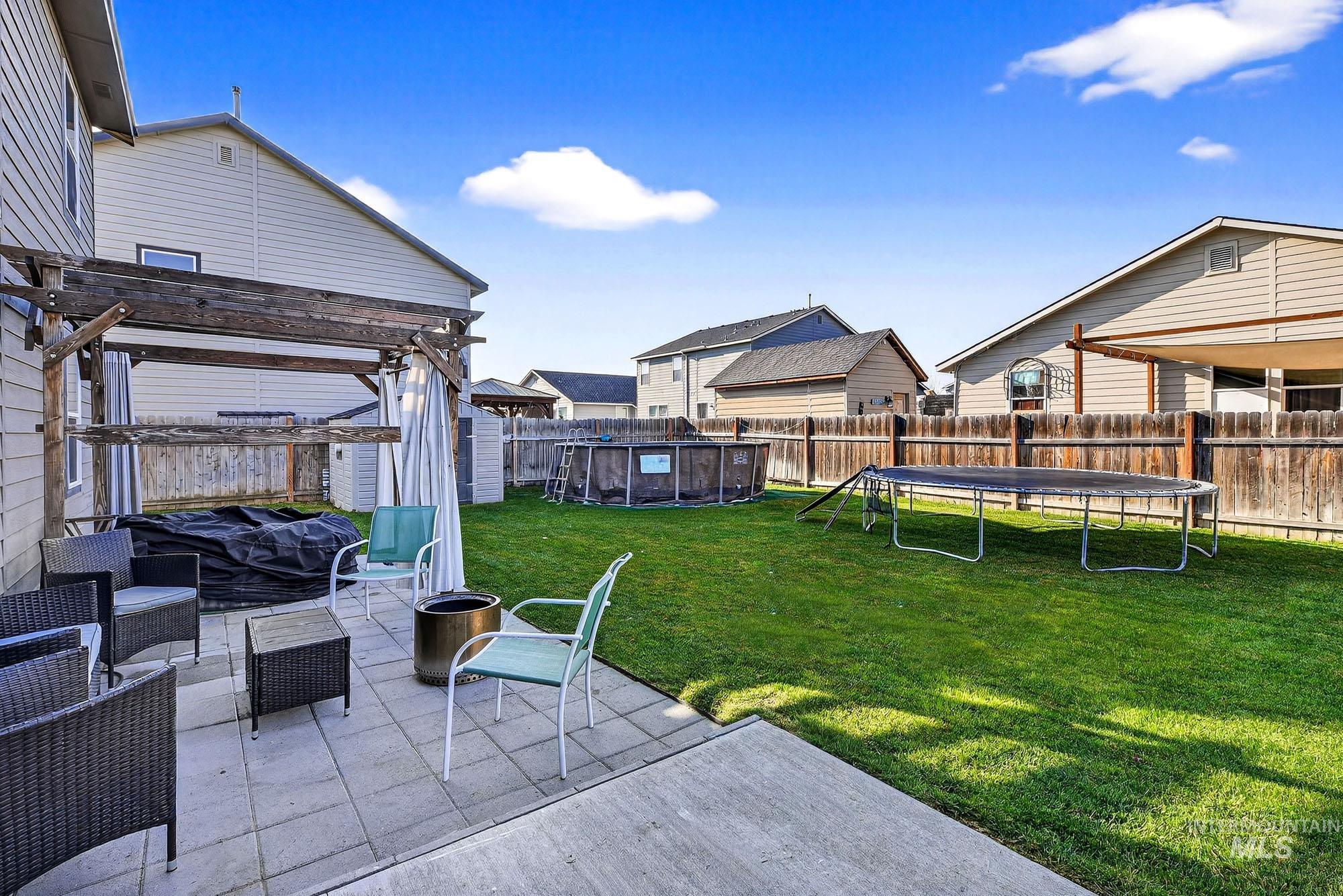 Fenced backyard with a trampoline, a patio area, an outdoor living space, and a pergola