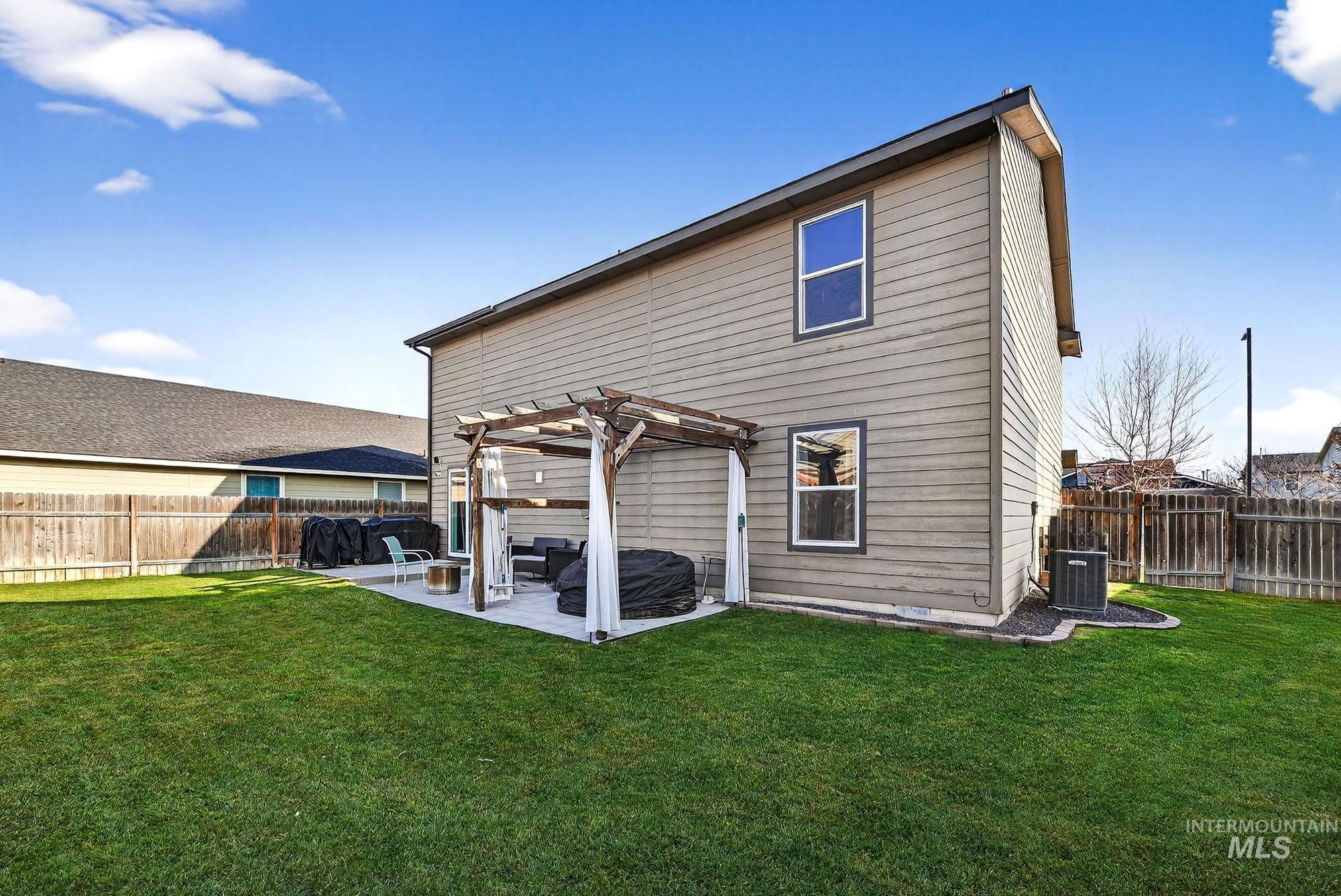 Back of property with a fenced backyard, a pergola, and a patio area