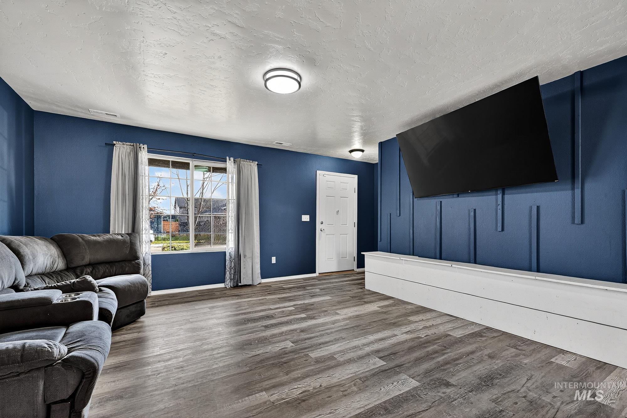 Living area with a textured ceiling and wood -like finished laminate floors