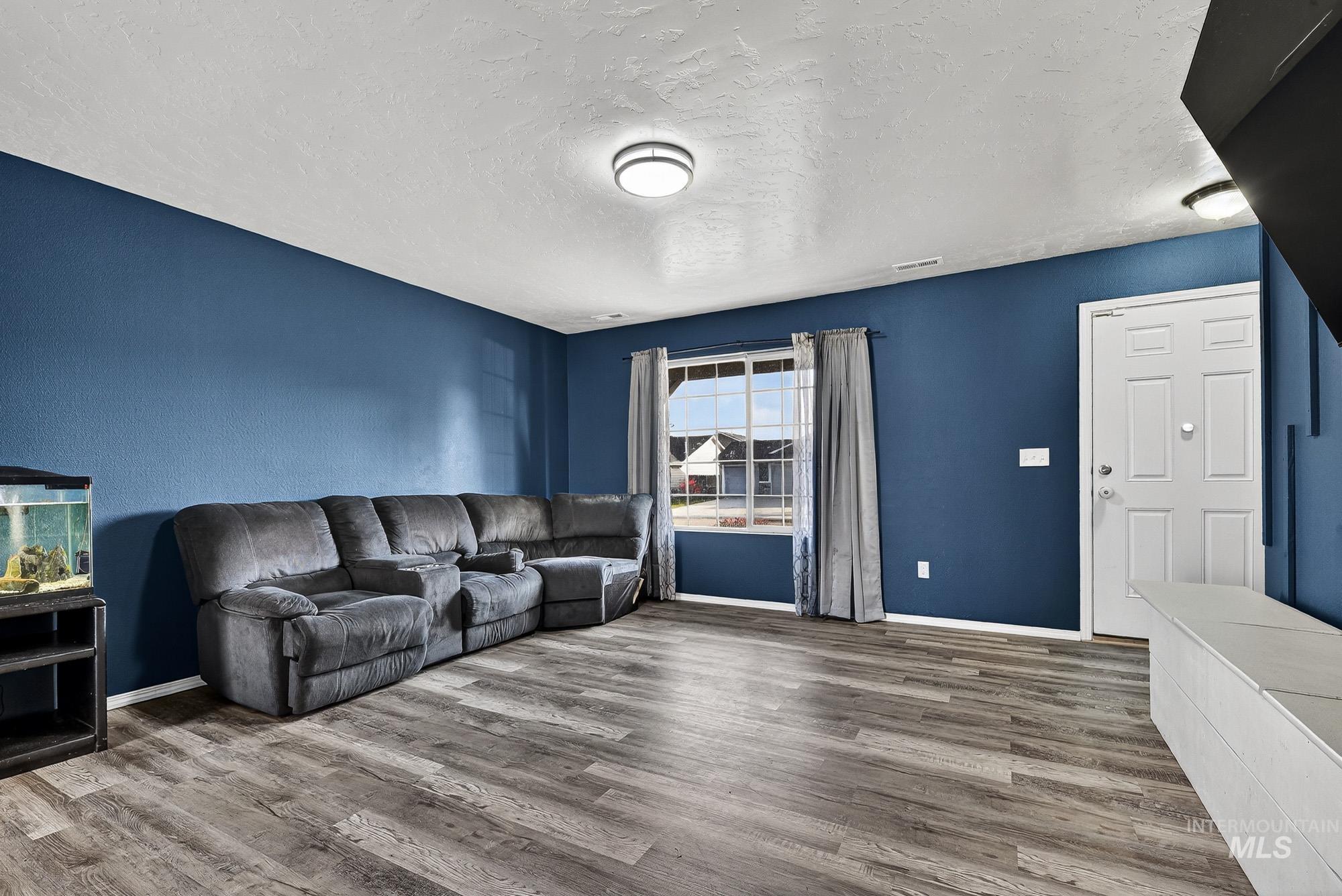 Living area with a textured ceiling and wood -like finished laminate floors
