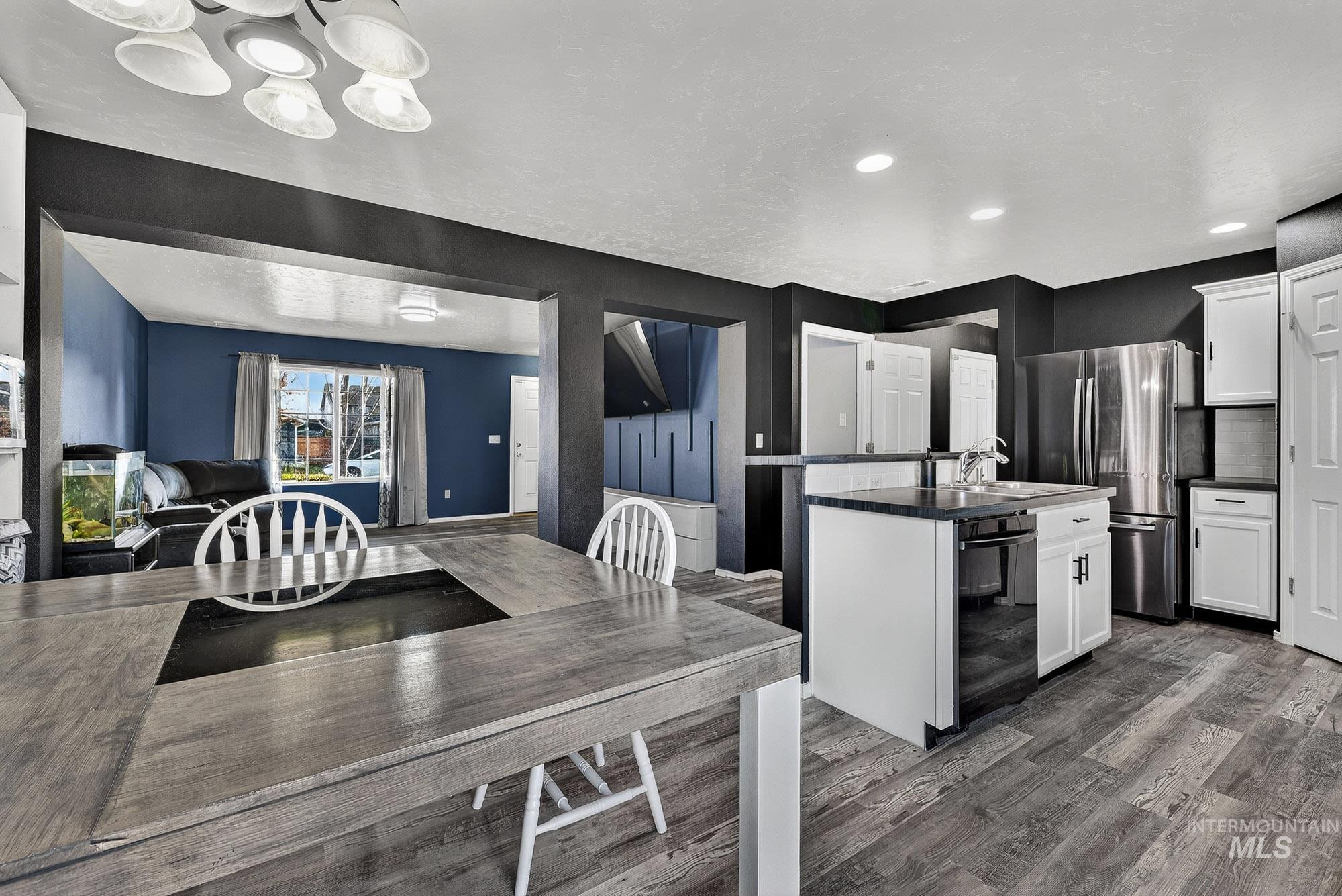 Kitchen with white cabinets, a center island with sink, freestanding refrigerator, and laminate wood-style flooring