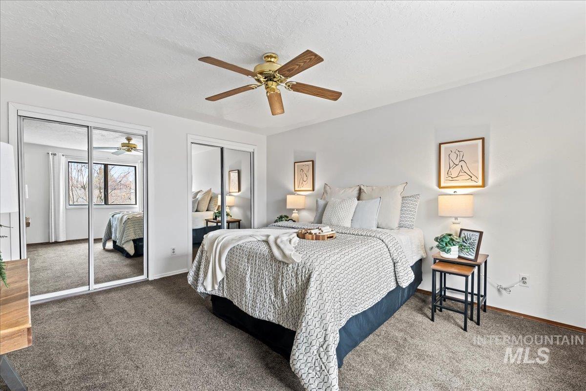 Carpeted bedroom featuring two closets, a ceiling fan, and a textured ceiling