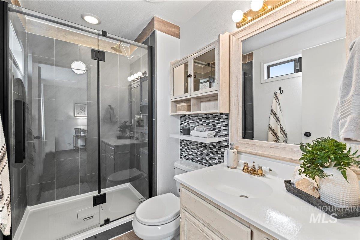 Bathroom with vanity, decorative backsplash, and a shower stall