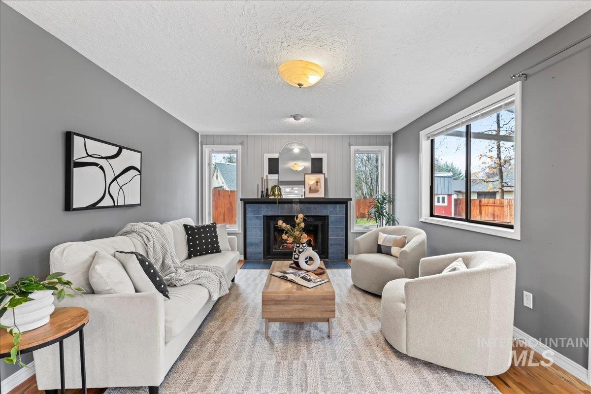 Living area with a tile fireplace, wood finished floors, a textured ceiling, and an accent wall