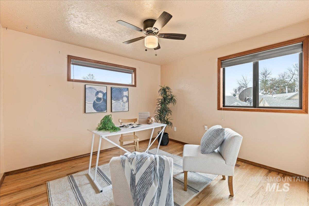 Office area with a textured ceiling, a ceiling fan, and light wood-style flooring