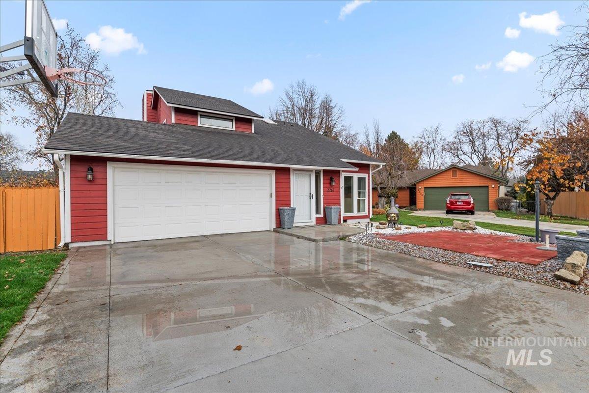 View of front facade featuring roof with shingles and driveway