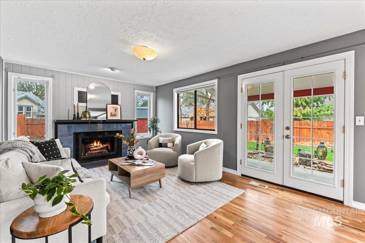 Living room with a fireplace, french doors, wood finished floors, and a textured ceiling