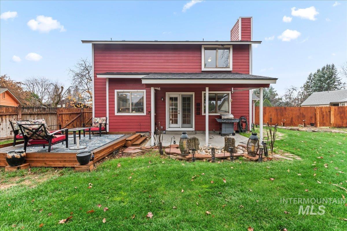 Back of property featuring a fenced backyard, french doors, a chimney, a wooden deck, and a patio