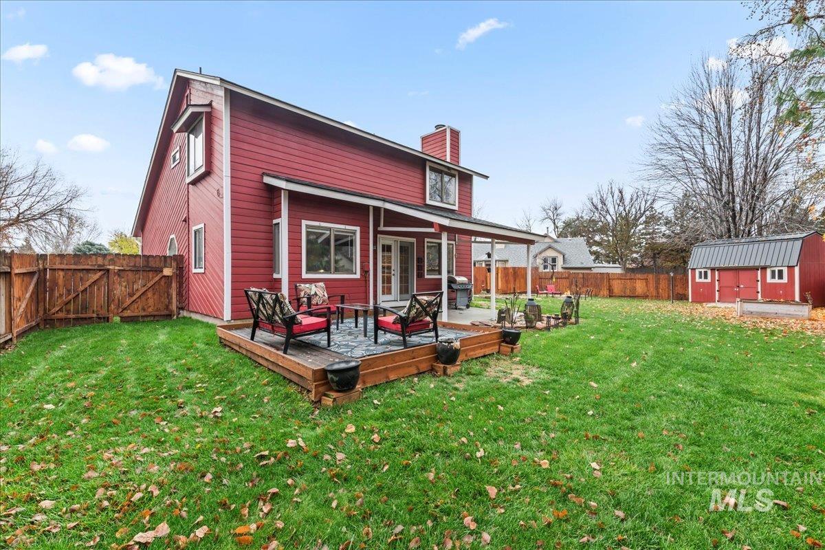 Rear view of property featuring a fenced backyard, a shed, a deck, a chimney, and french doors