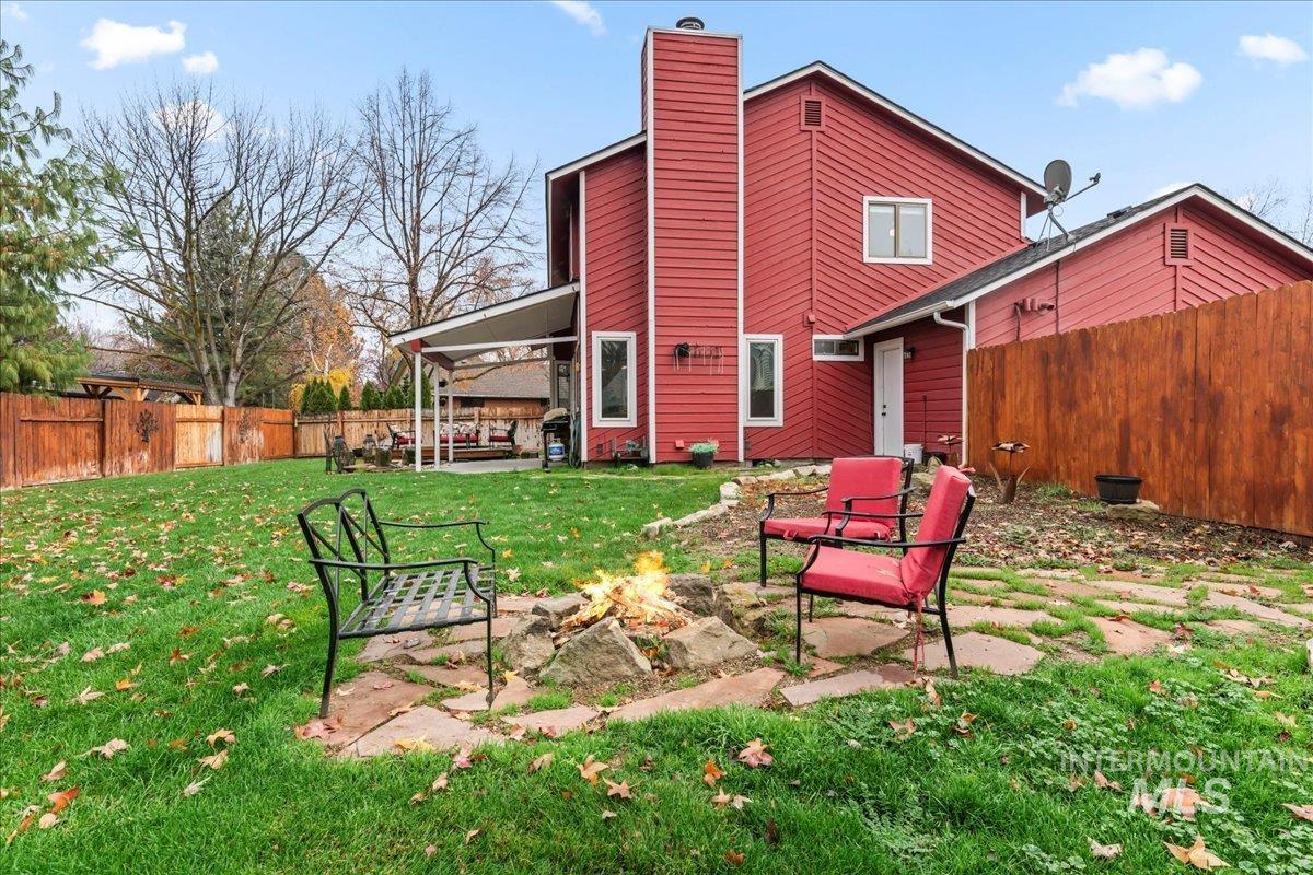 Rear view of house featuring a patio, a fenced backyard, an outdoor fire pit, and a chimney