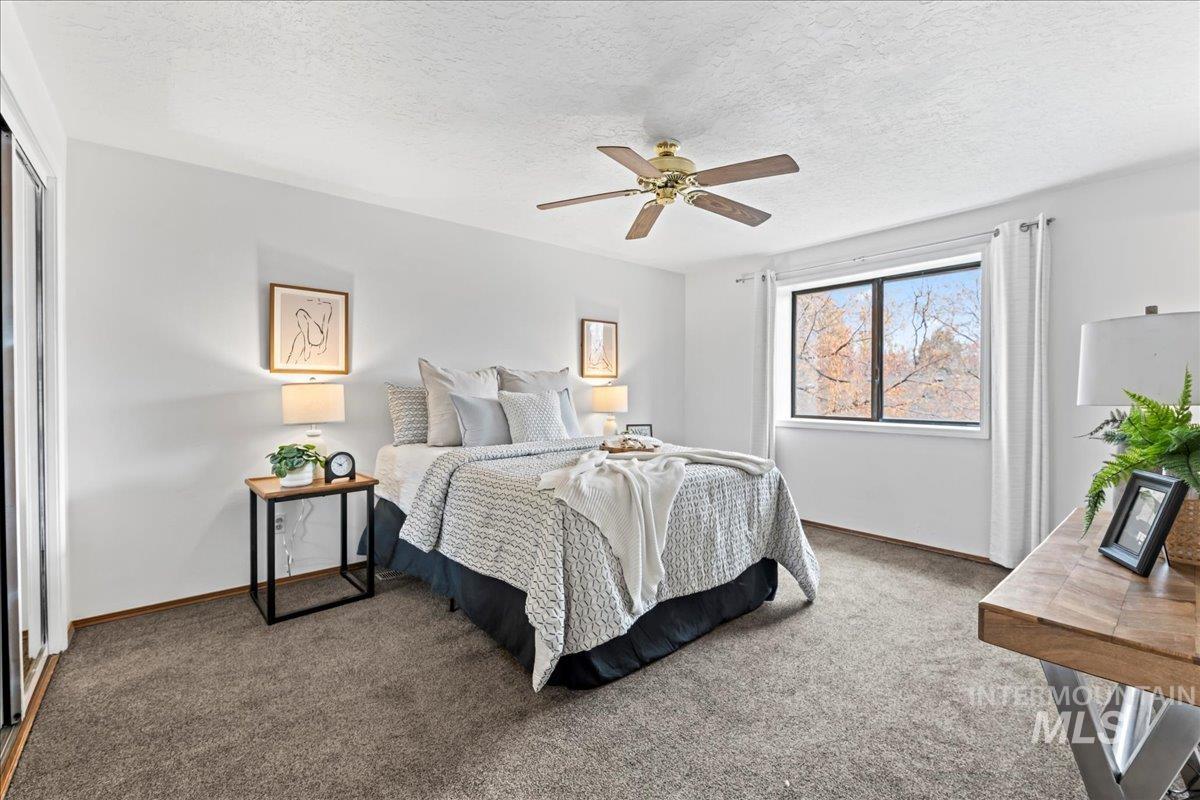 Carpeted bedroom with a textured ceiling and a ceiling fan