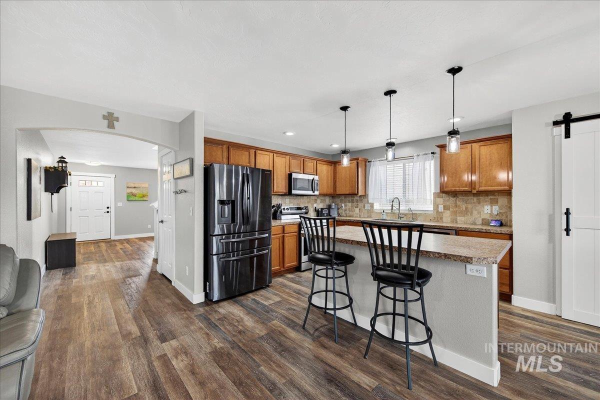 Kitchen with a barn door, stainless steel appliances, a kitchen breakfast bar, a center island, and brown cabinets