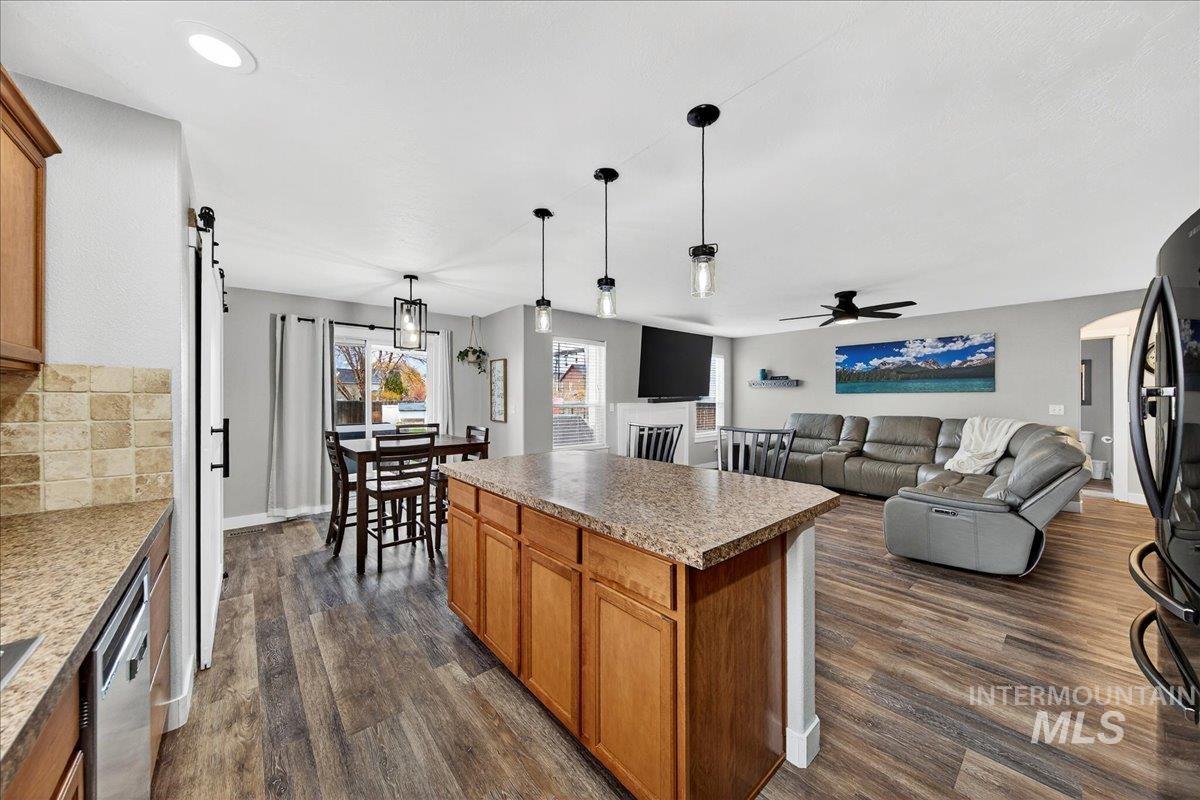 Kitchen featuring a barn door, brown cabinetry, decorative light fixtures, backsplash, and a center island