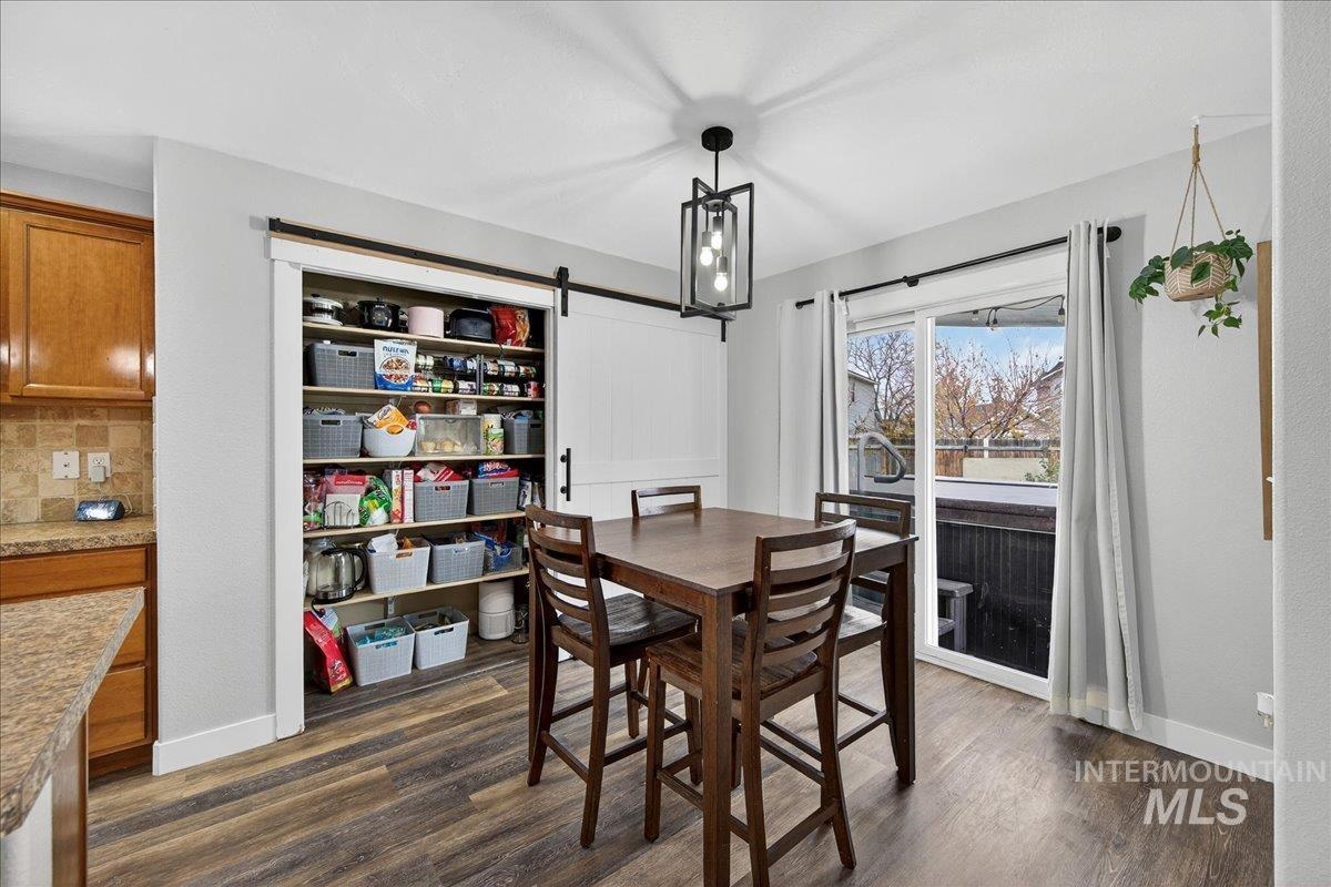 Dining space with a barn door and dark wood finished floors