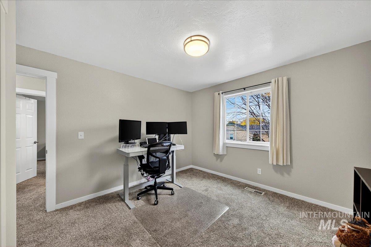 Carpeted home office featuring baseboards and a textured ceiling