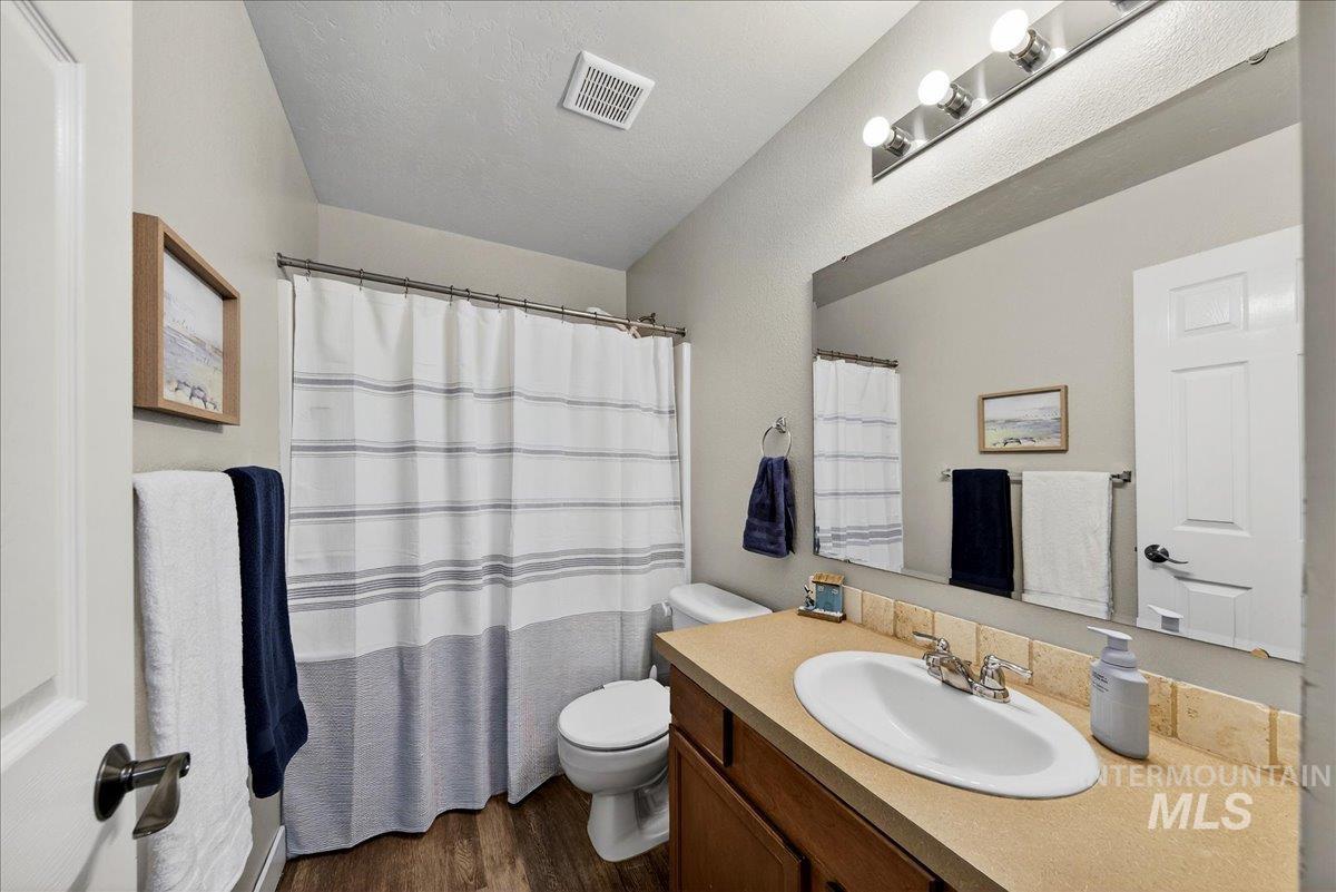 Bathroom featuring a shower with curtain, vanity, dark wood-style flooring, and a textured ceiling