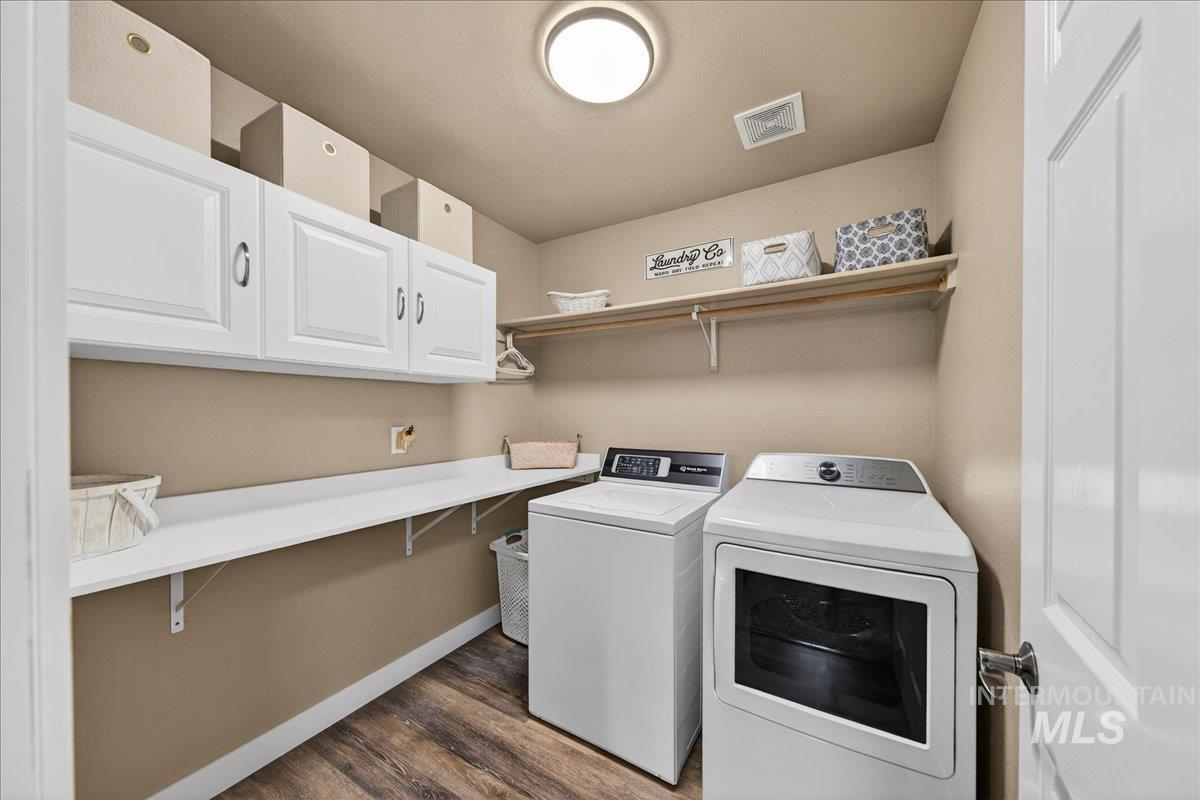 Laundry area with washing machine and dryer, cabinet space, and dark wood-type flooring