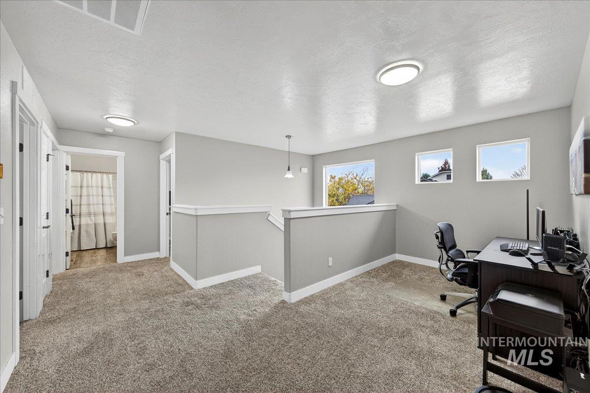 Home office featuring a textured ceiling and light carpet