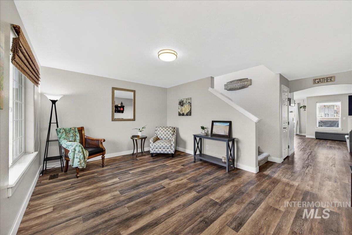 Living area featuring stairs, dark wood-style flooring, and arched walkways