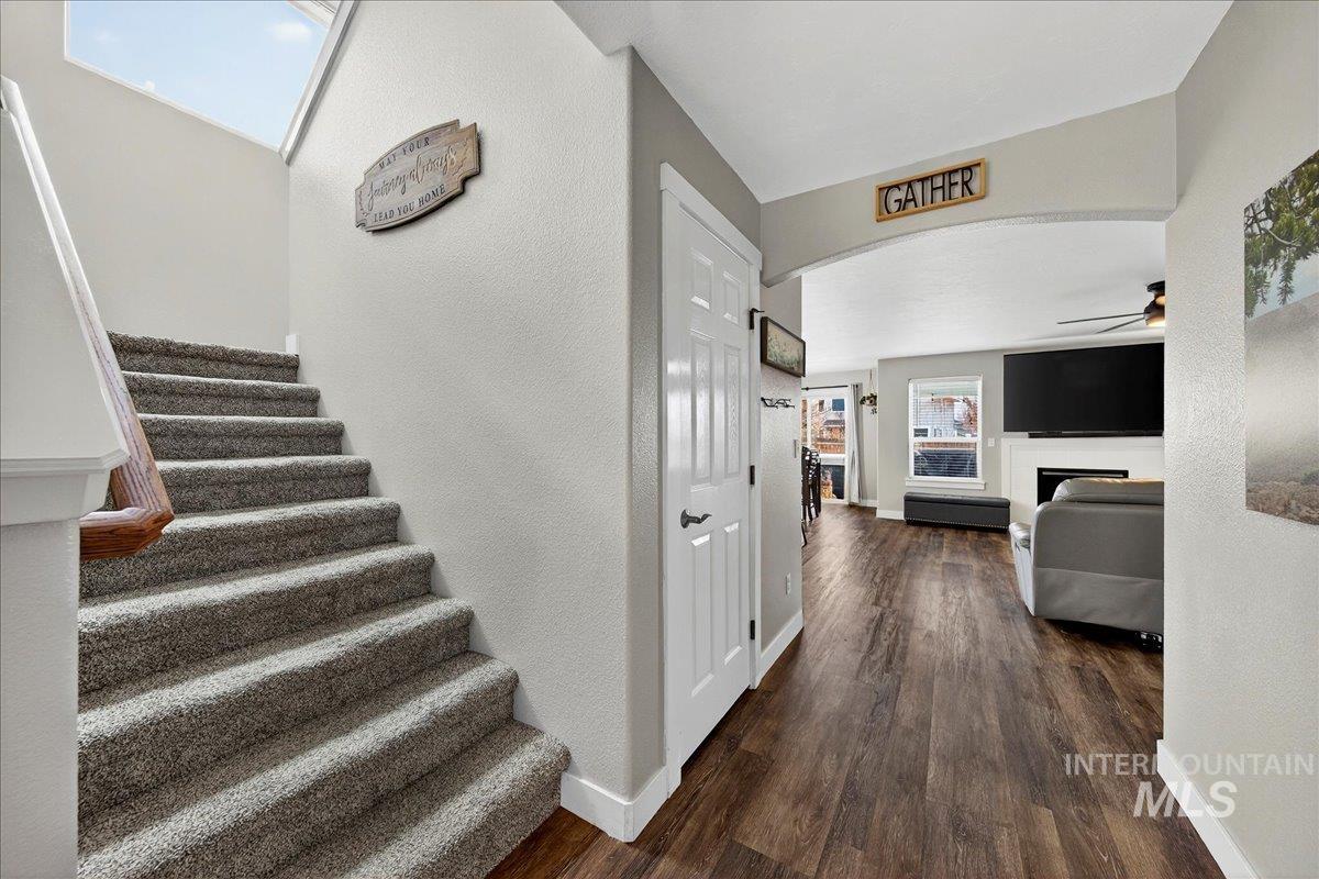 Stairs featuring a fireplace, wood finished floors, arched walkways, a textured wall, and a ceiling fan