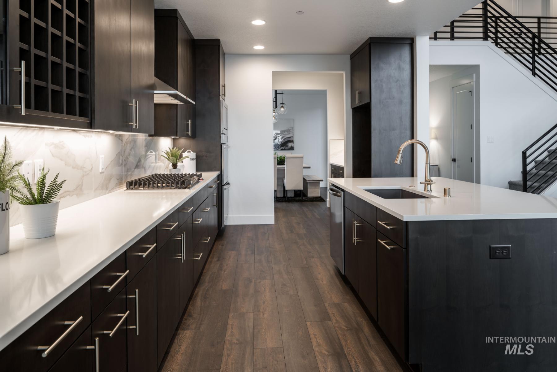 Kitchen with dark wood finished floors, recessed lighting, a center island with sink, wall chimney exhaust hood, and modern cabinets