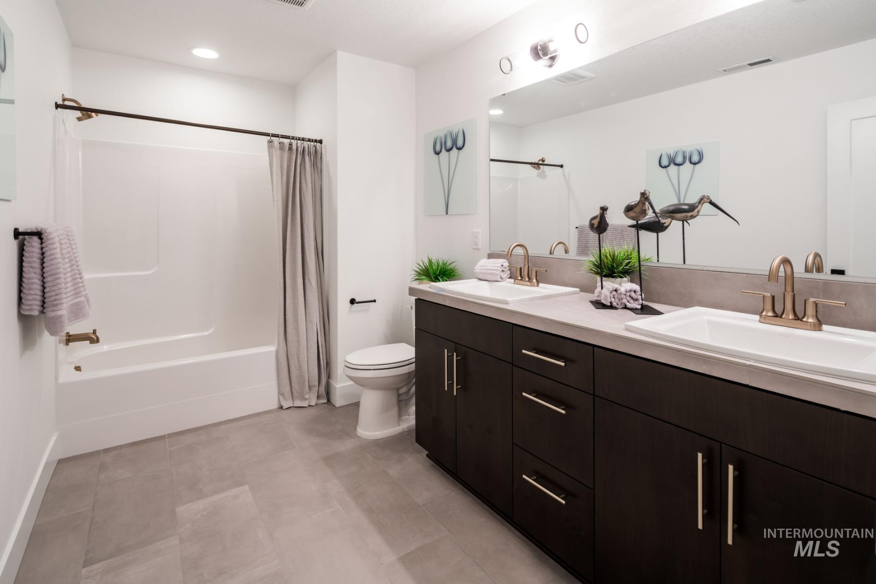 Full bathroom featuring double vanity, shower / bath combo, and recessed lighting