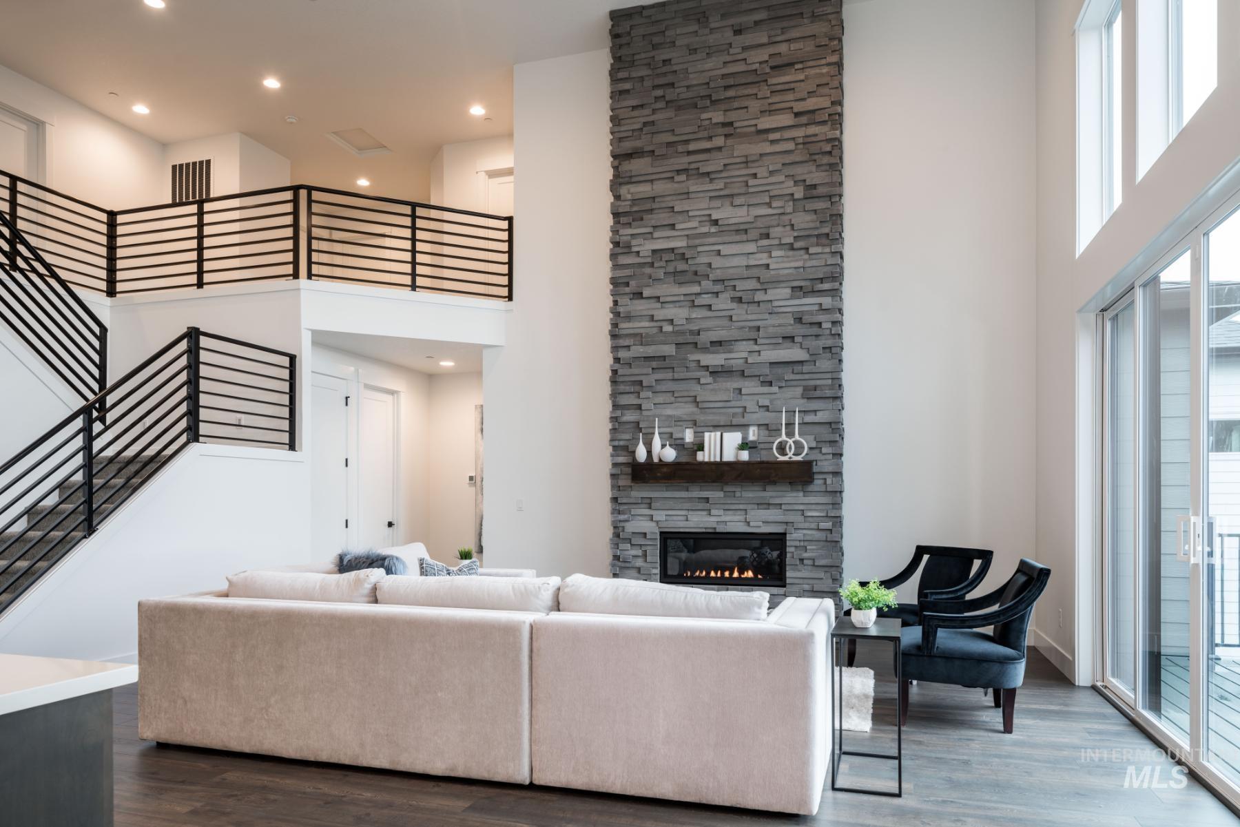 Living area with a towering ceiling, stairway, dark wood-style floors, a fireplace, and plenty of natural light