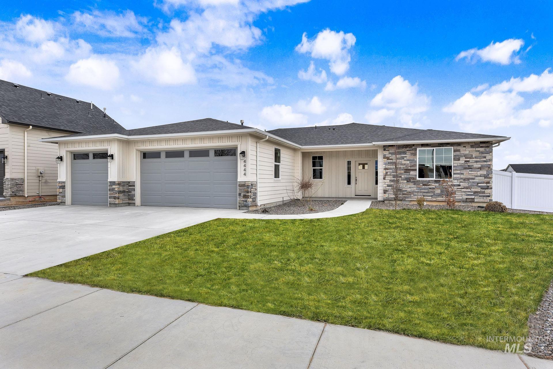 View of front facade with stone siding, an attached garage, driveway, and a shingled roof