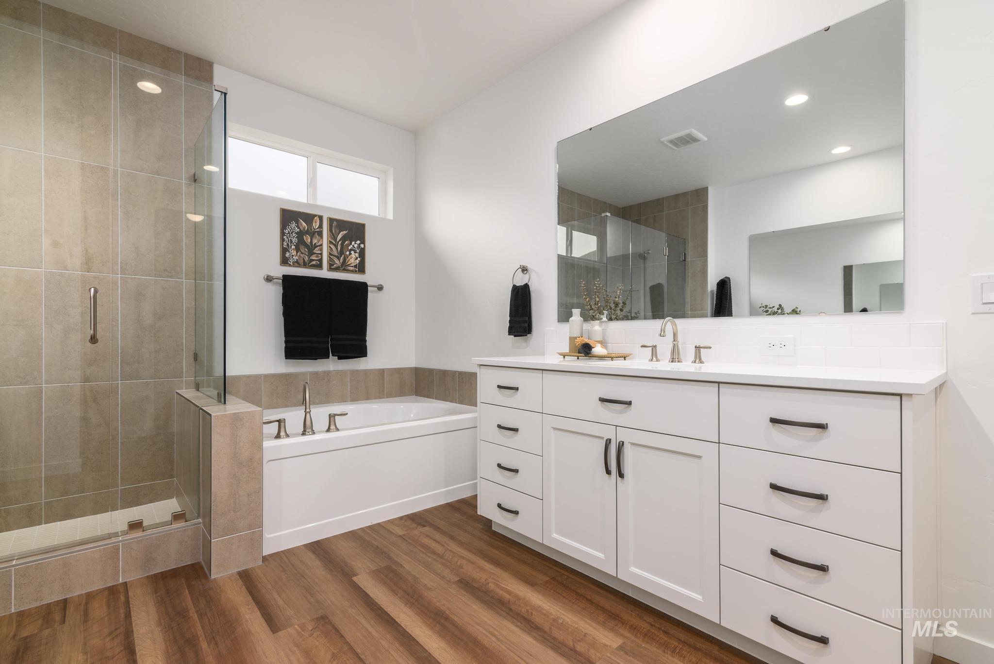 Full bath featuring vanity, dark wood-style flooring, a bath, and a stall shower