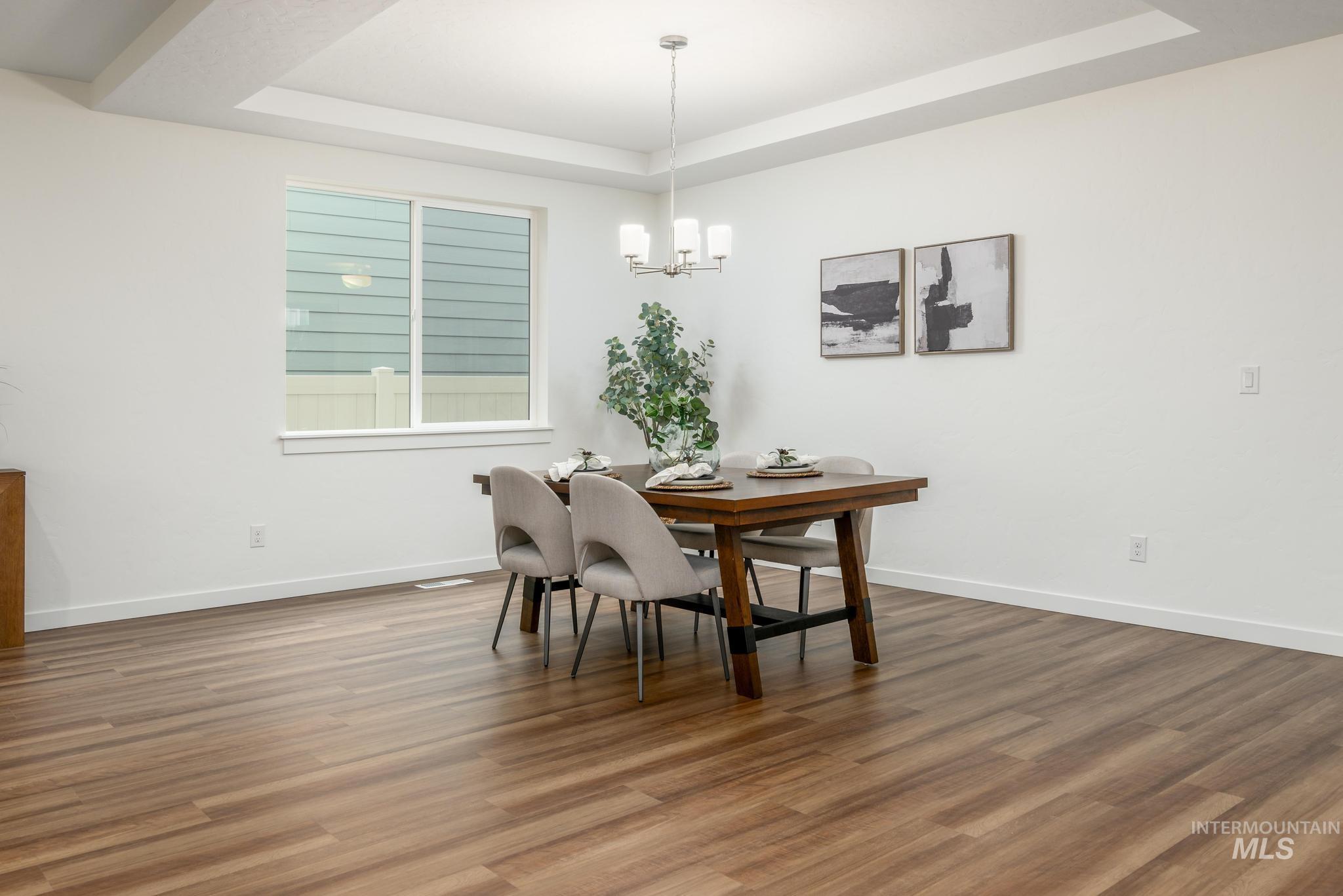 Dining space featuring a tray ceiling, wood finished floors, and a chandelier