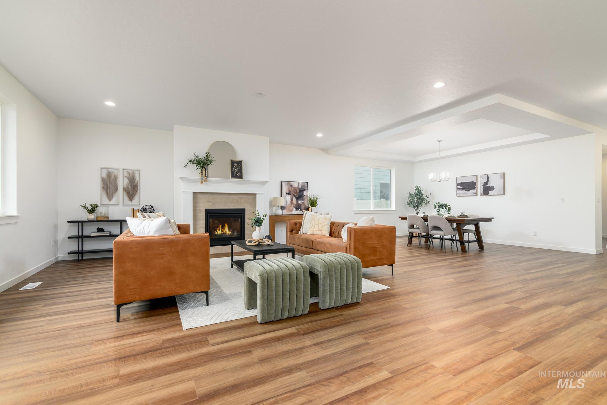 Living area with a glass covered fireplace, light wood finished floors, recessed lighting, and a chandelier