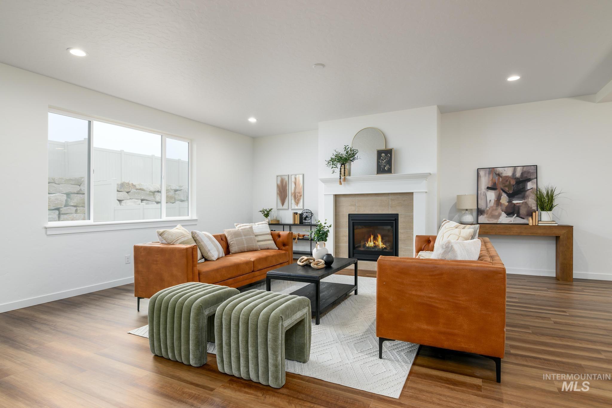 Living room with a tiled fireplace, wood finished floors, and recessed lighting