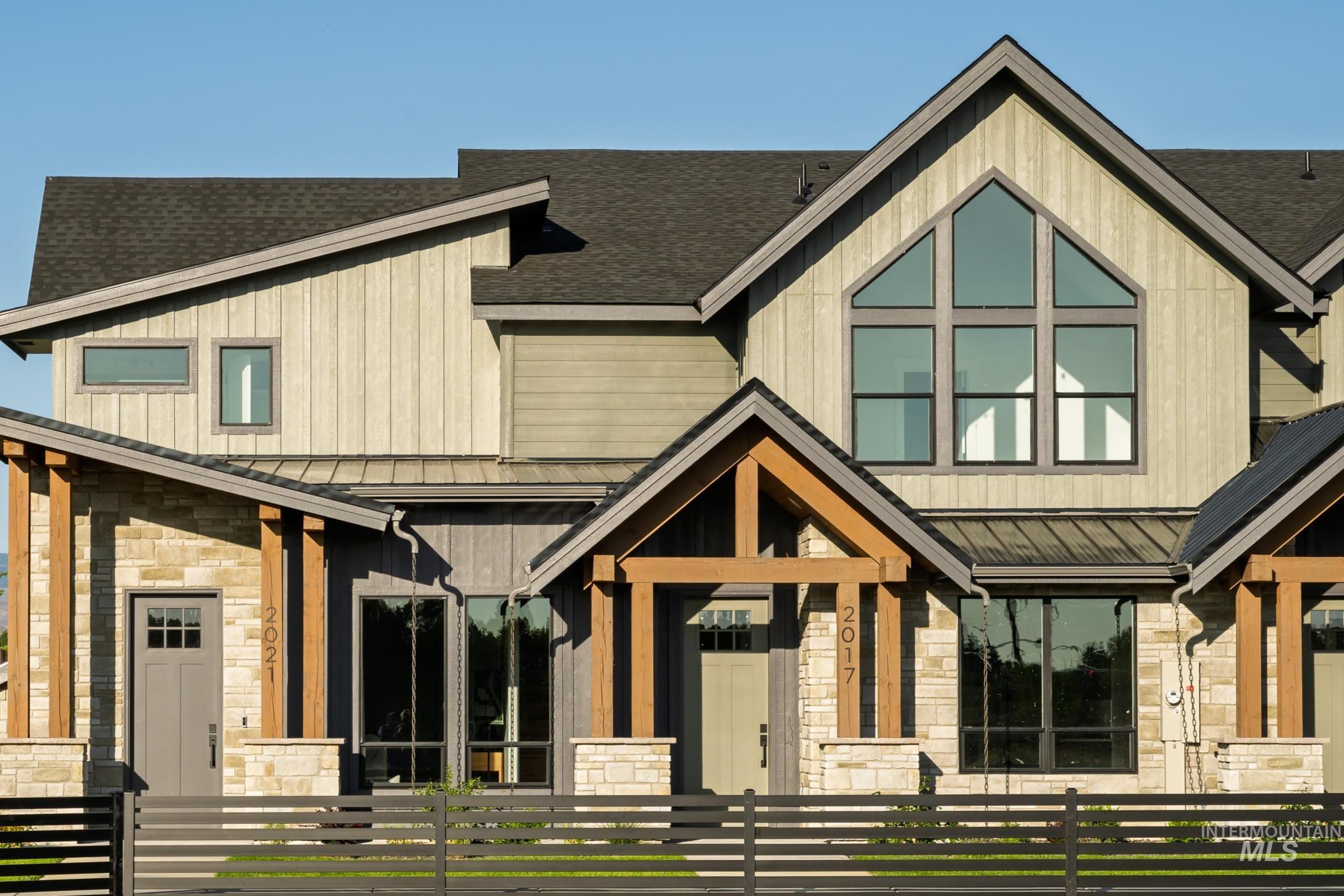 View of front of home with stone siding, a standing seam roof, a fenced front yard, and a shingled roof