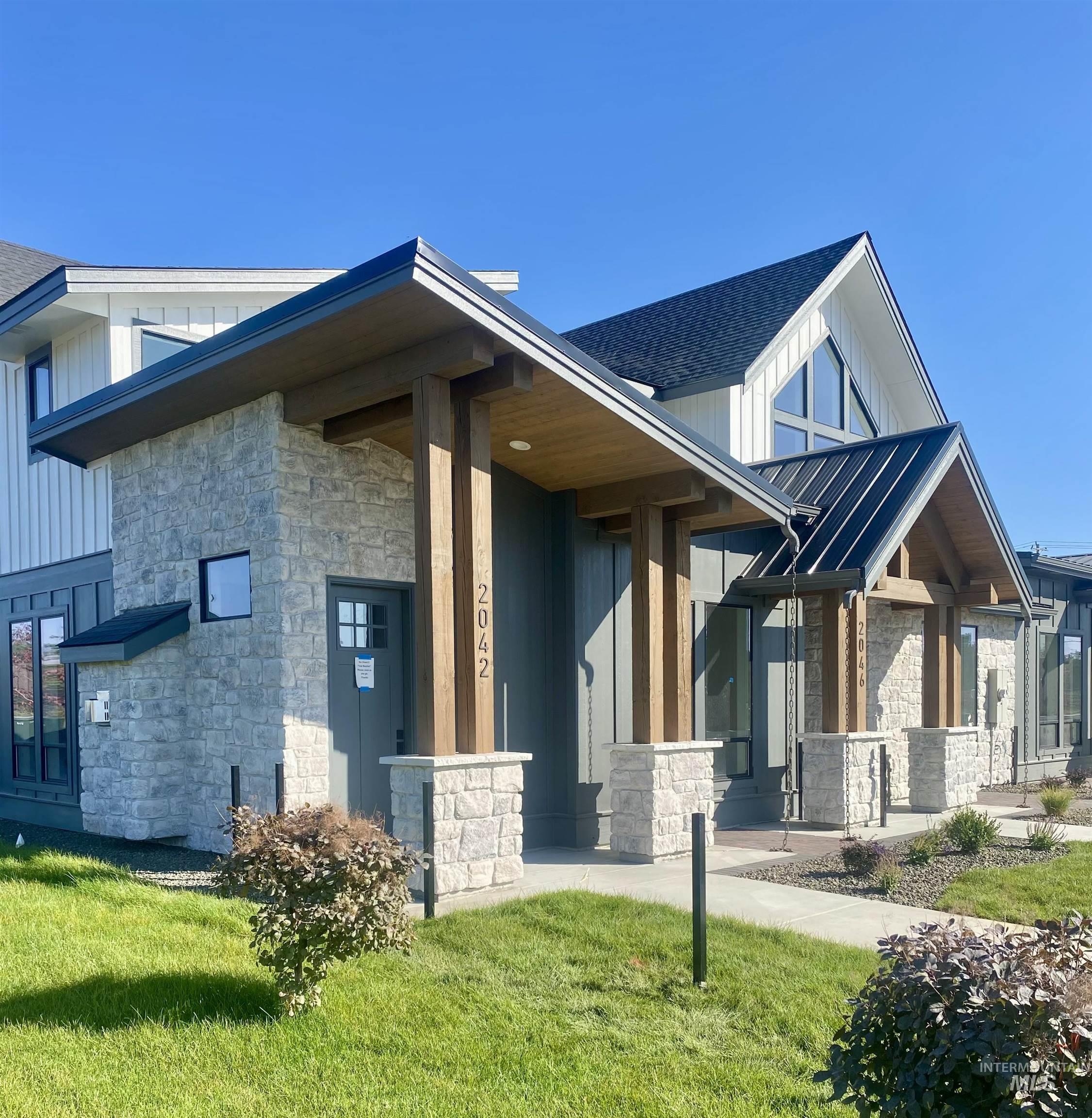 Entrance to property featuring stone siding, board and batten siding, a yard, a porch, and a shingled roof