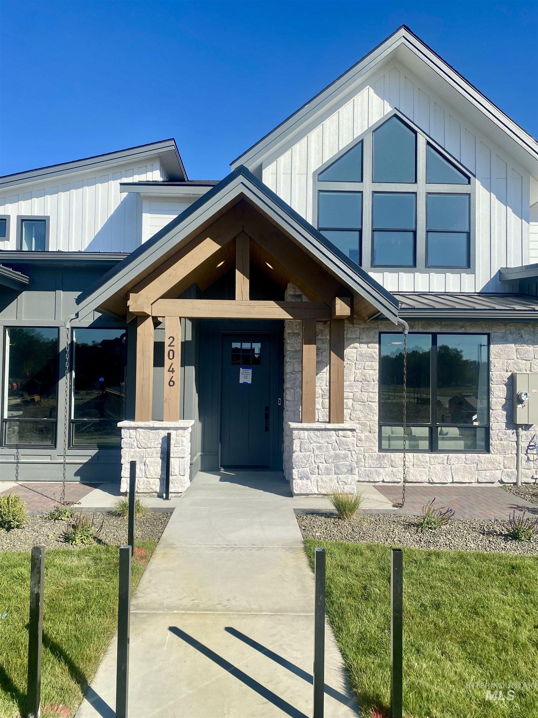Entrance to property with stone siding, a lawn, a standing seam roof, and board and batten siding