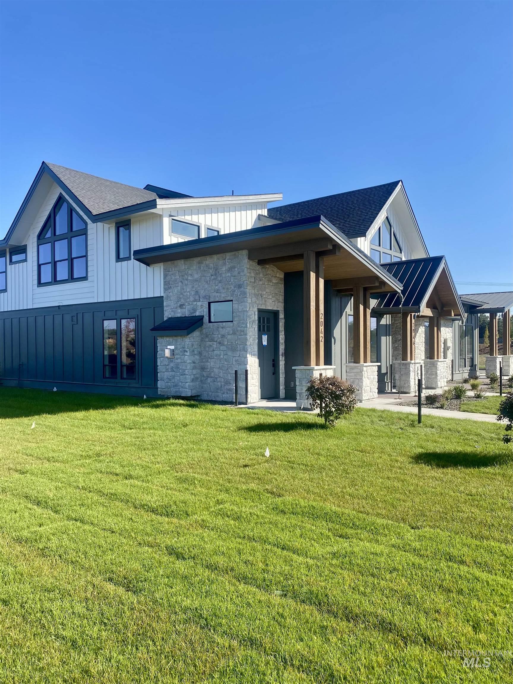 Rear view of property with board and batten siding, a yard, stone siding, a porch, and a standing seam roof