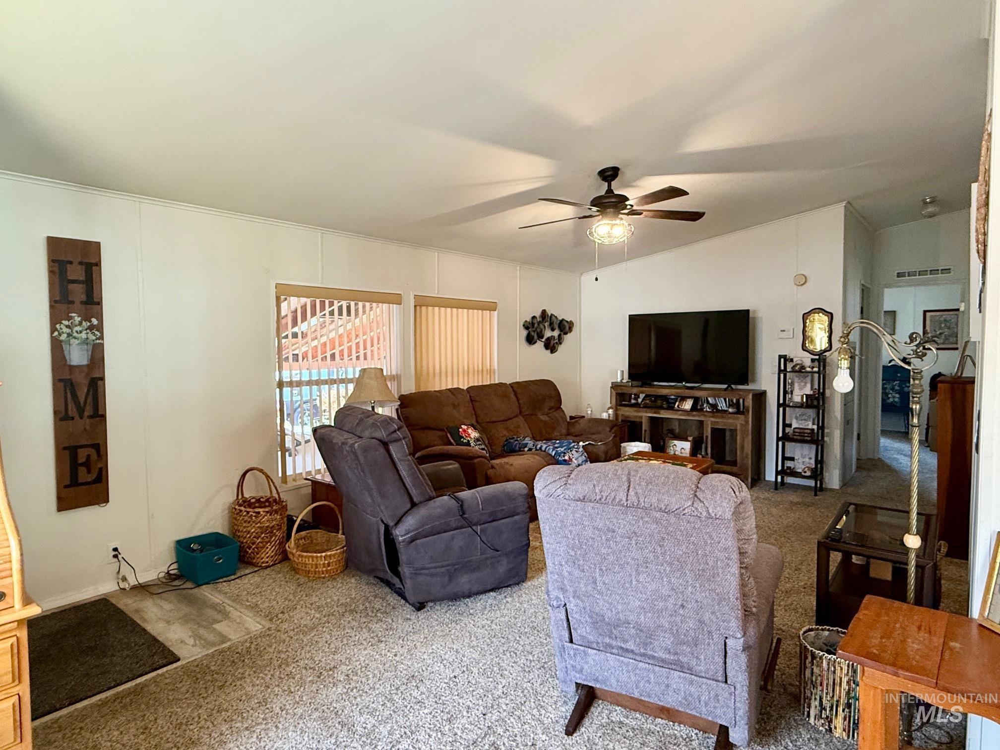 Living area featuring lofted ceiling, ceiling fan, and carpet