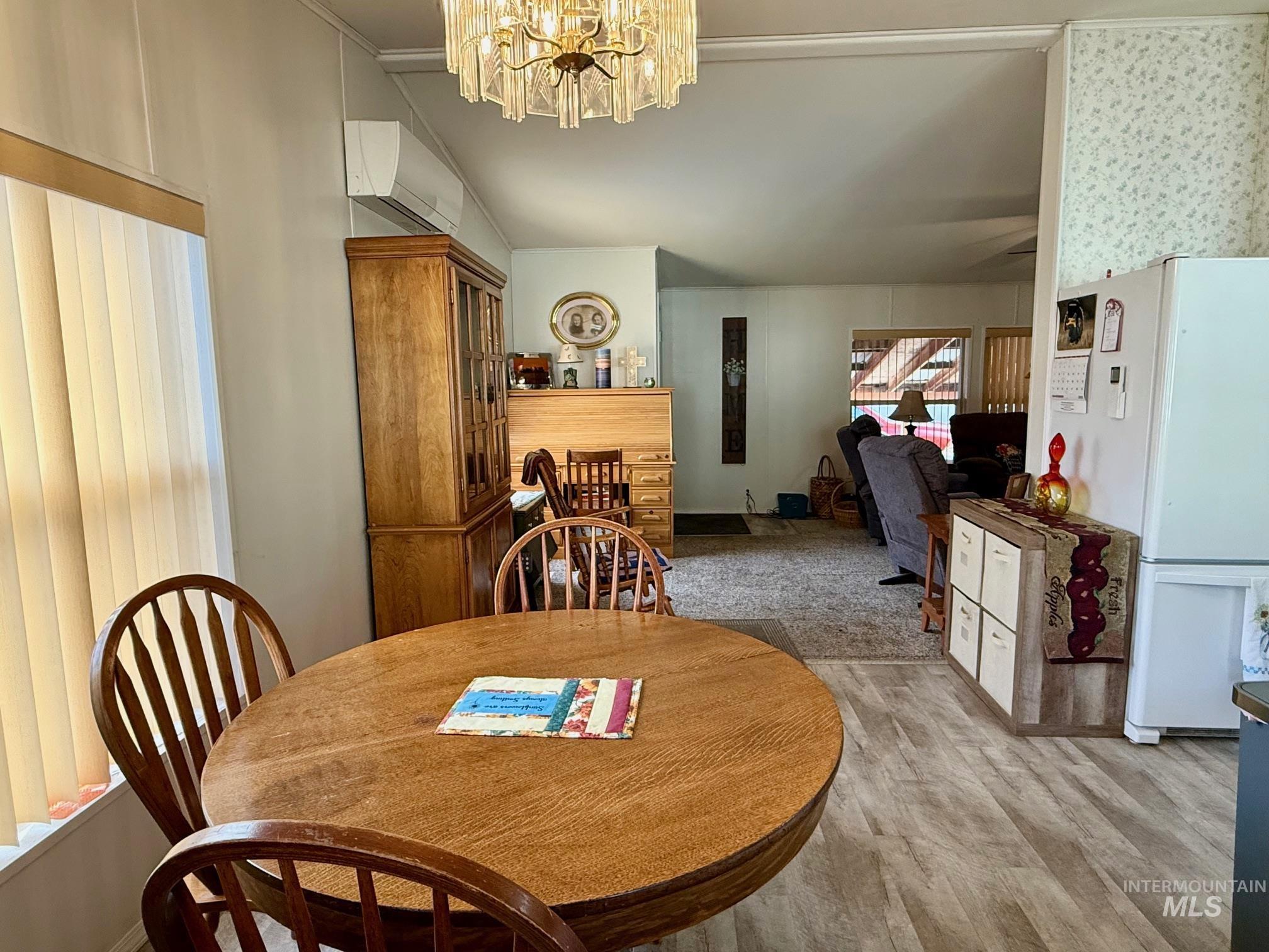 Dining room with a chandelier, light wood-style flooring, and a wall mounted air conditioner
