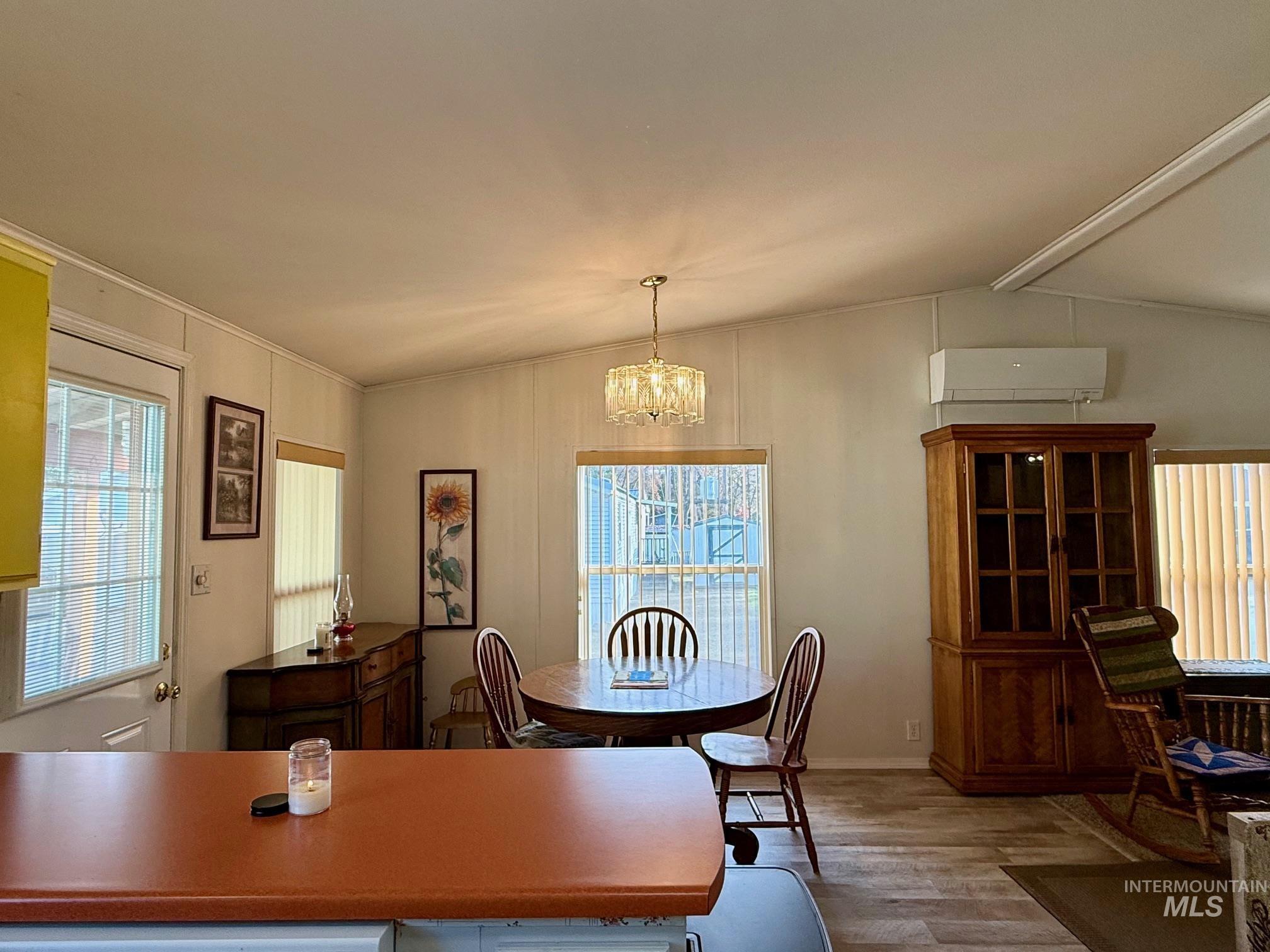 Dining space featuring light wood-style flooring, a chandelier, and a wall unit AC