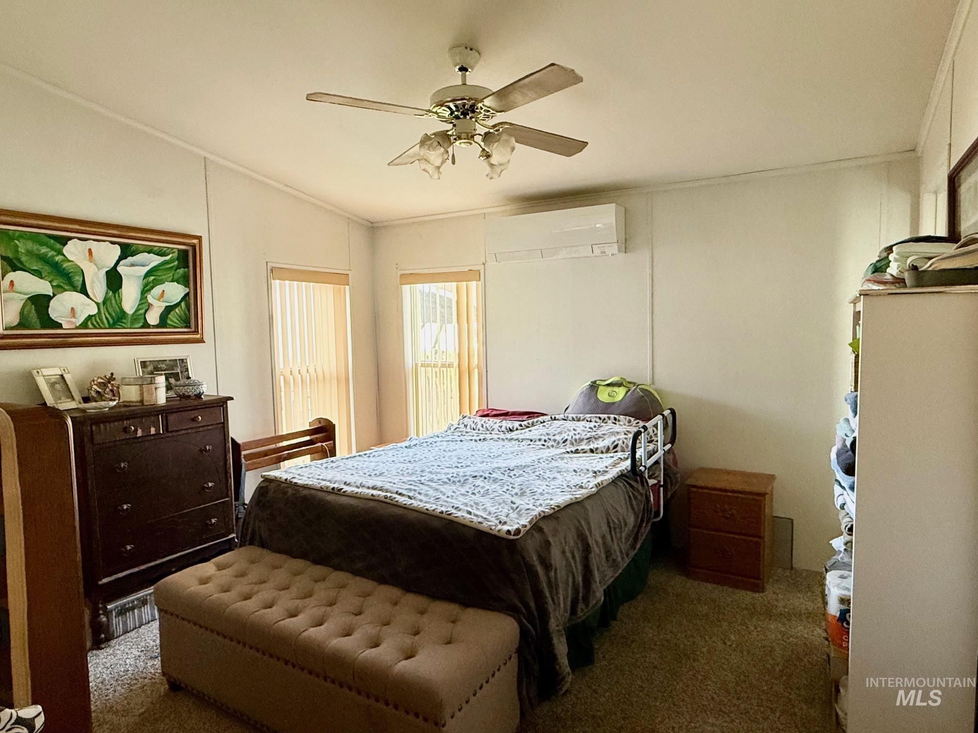 Carpeted bedroom featuring ceiling fan, lofted ceiling, and a wall mounted AC